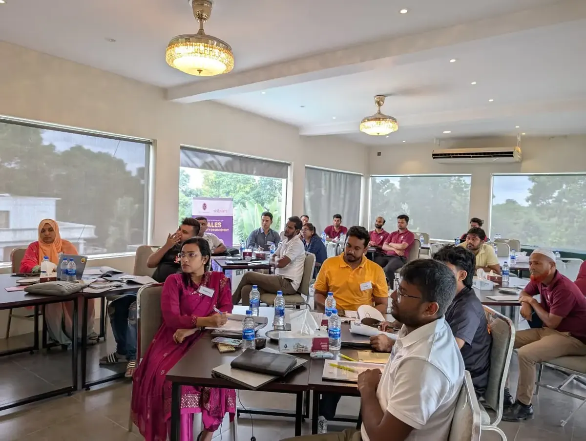 Participants taking notes at tables during a sales capability workshop