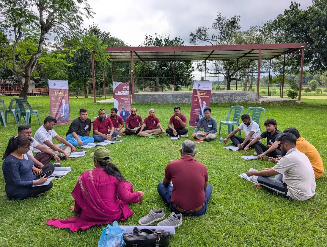 Participants sitting in a circle on the grass during an outdoor sales workshop exercise